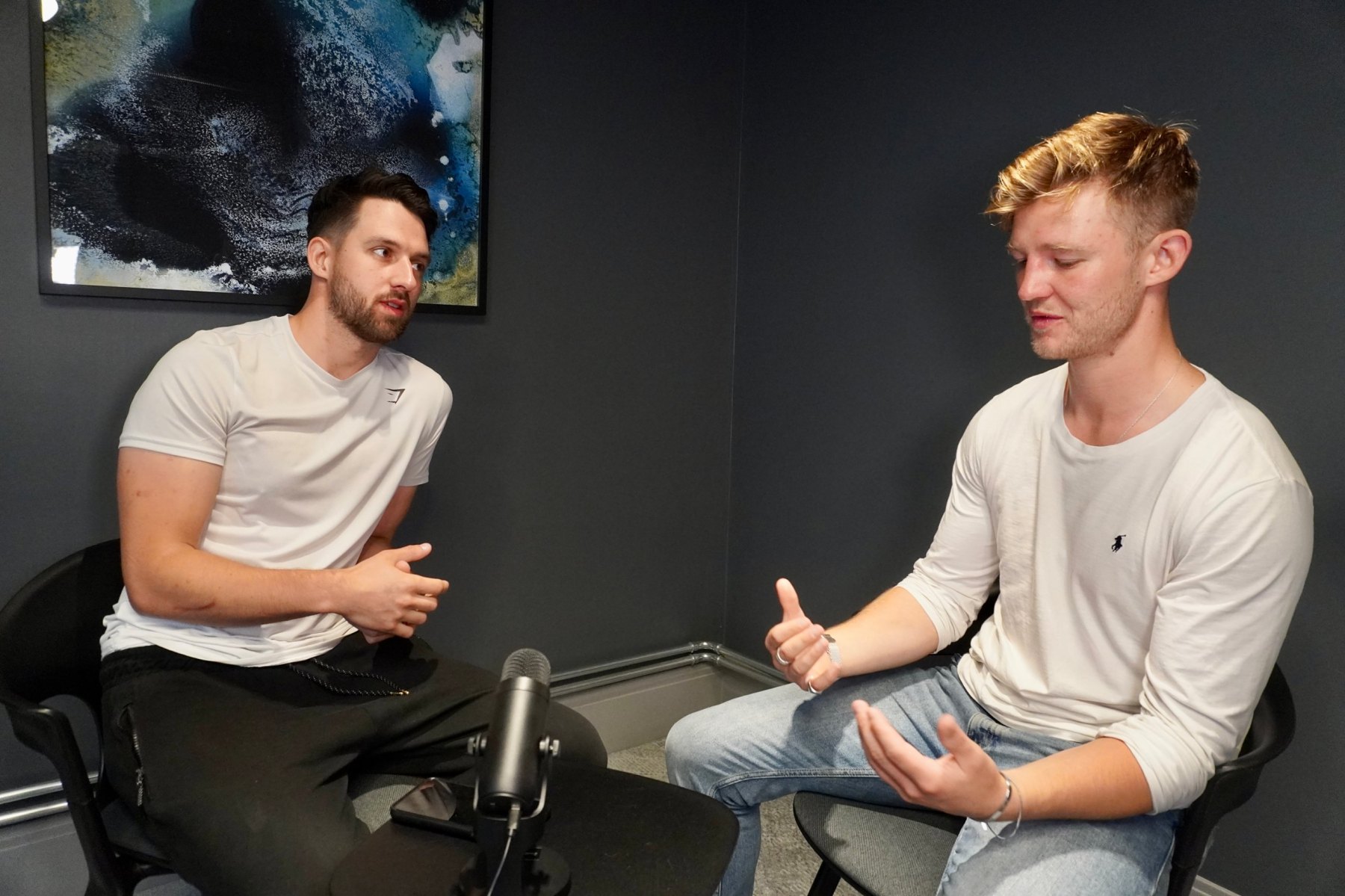 Two men in conversation across a table with a microphone
